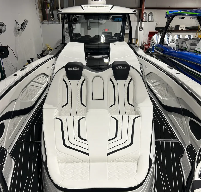 Luxurious white boat interior with black accents, featuring a double seat layout with custom stitching, headrests embroidered with the MTI logo, and non-slip black flooring with white trim.