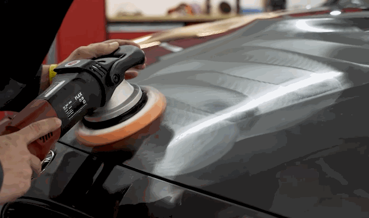 Detailer using a polishing machine to prepare a BMW hood for ceramic coating at a Chesterfield, MO auto detailing shop.