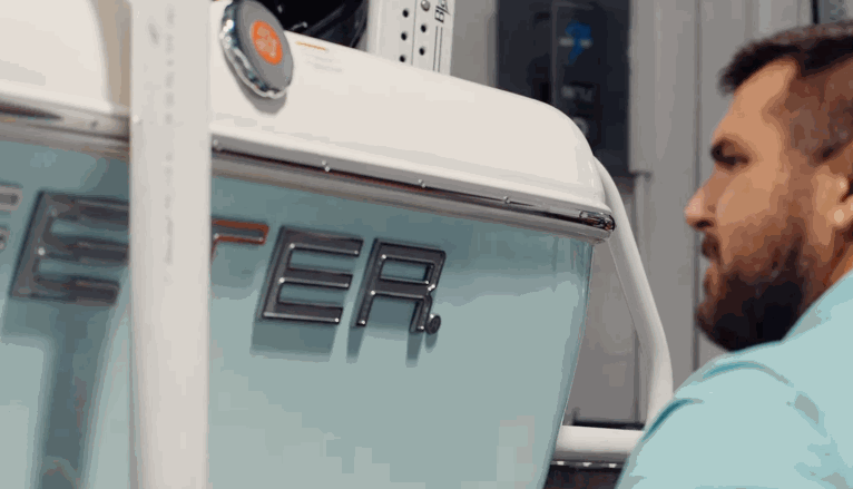 Man inspecting the side of a boat labeled “ETER” after applying a smooth protective coating