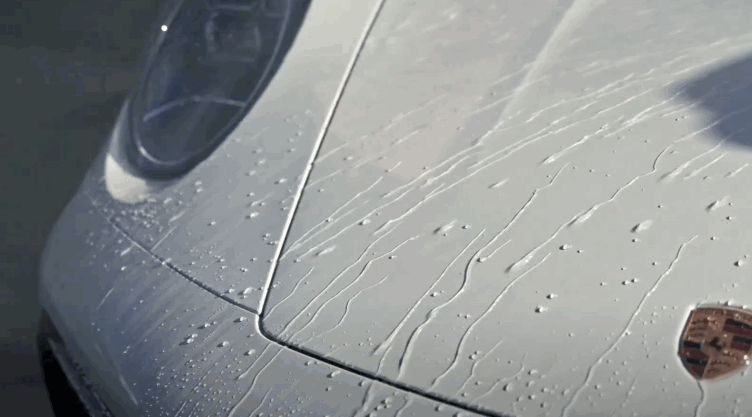Close-up of a sports car hood with ceramic coating showing water beading and smooth runoff.