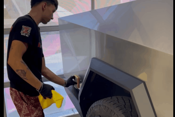 An OCDetailers employee polishes the side panel of a silver vehicle to maintain the quality of its paint protection film.