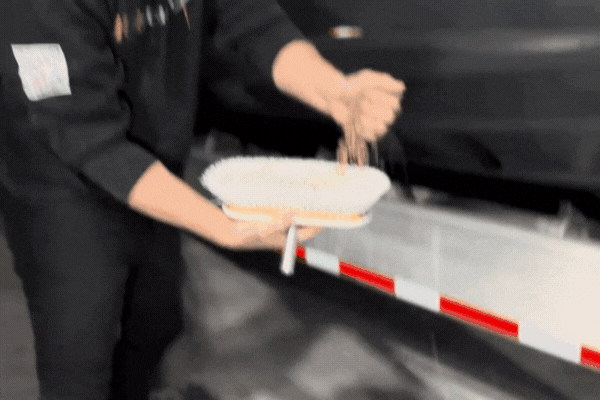 A marine detailing technician demonstrates the hydrophobic effect of Paint Protection Film (PPF) by pouring water over a protected boat surface in Osage Beach, showing how the water beads and runs off without sticking. This illustrates The Role of PPF in shielding boats from water damage and buildup.